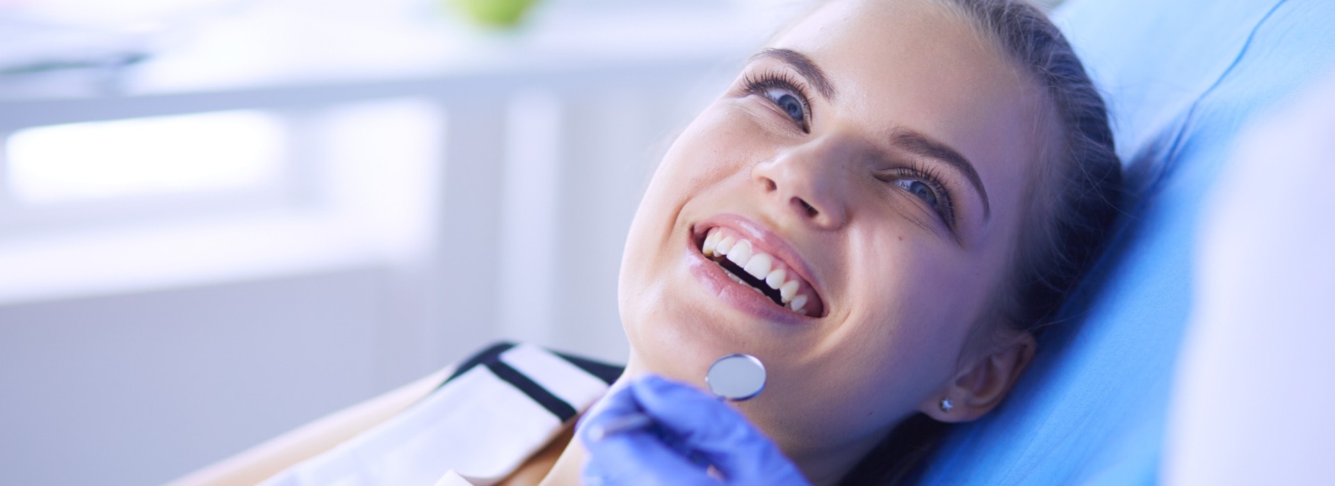 Junge weibliche Patientin mit hübschem Lächeln bei der zahnärztlichen Untersuchung in einer Zahnarztpraxis.